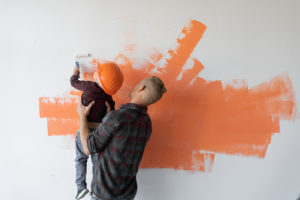 Father and son paints wall Orange